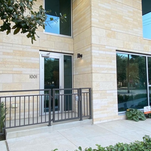 a building with a fence and bushes in front of it