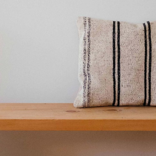 a wooden bench with a striped pillow on it